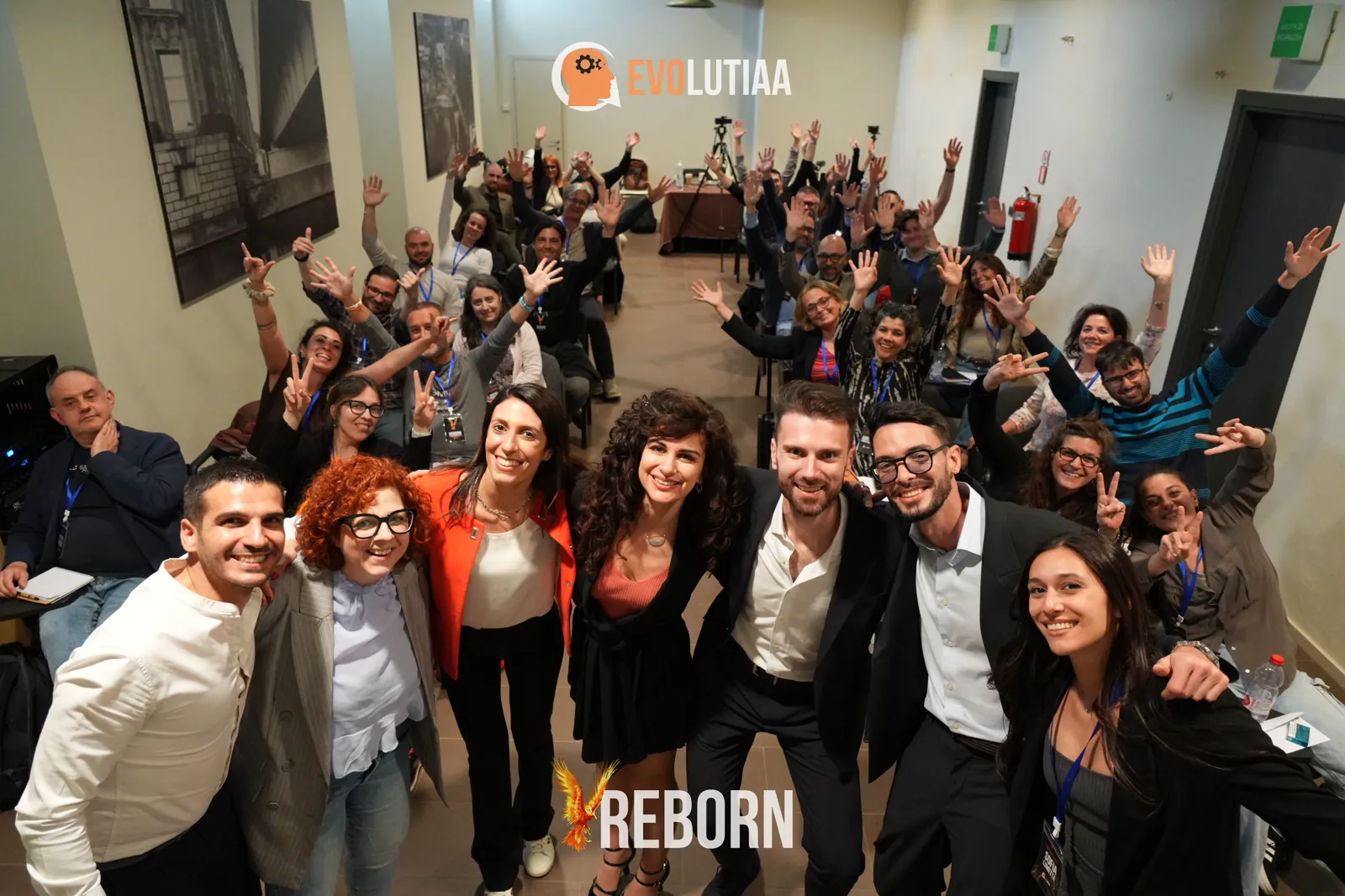 Partecipanti all'evento dal vivo REBORN di Evolutiaa con le mani alzate, insieme ai fondatori Andrea e Selene